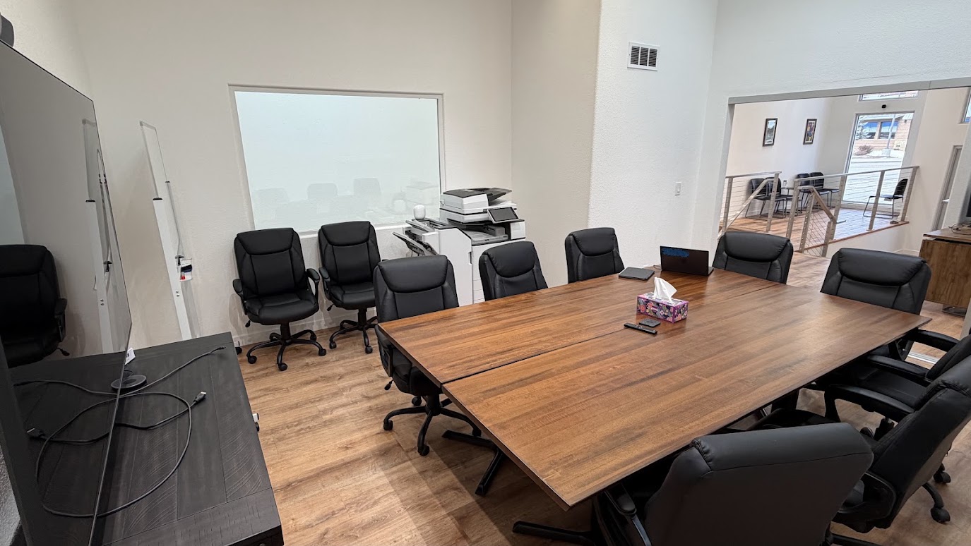 The renovated interior of 821 South Main, with white walls, wood floors, skylights, and a modern conference room