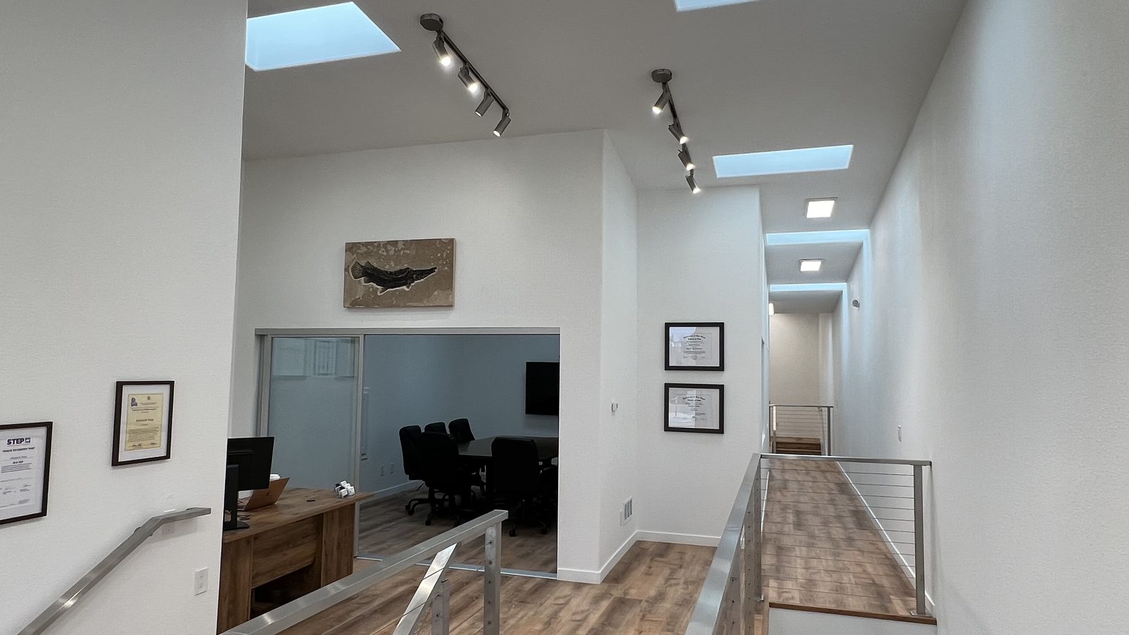 The light-filled upper level of 821 South Main, with skylights, wood floors, cable railings, and a glass-walled conference room